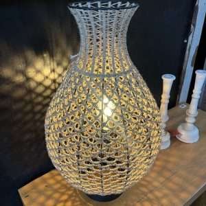 Abajur de mesa artesanal feito de fibra natural trançada, criando padrões de luz e sombra aconchegantes para mesas de cabeceira e laterais.