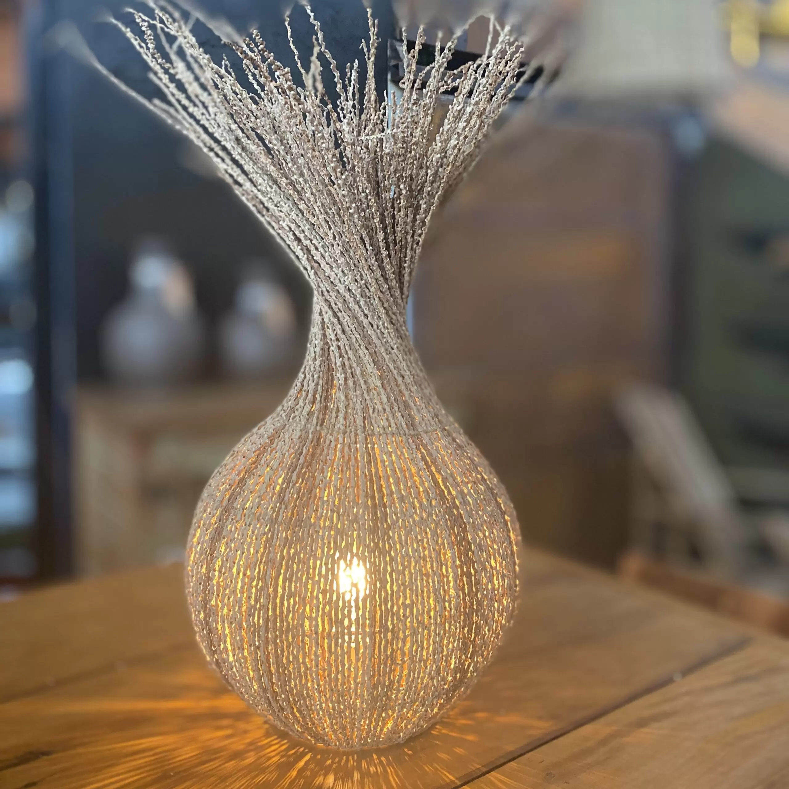 Luminária de mesa Moringa feita de fibra de açaí trançada, com base redonda e padrão de trança artesanal, criando uma iluminação suave e aconchegante.