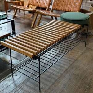 Banco sapateira com assento de madeira ripada, estrutura em ferro e tampo articulado, estilo industrial rústico.