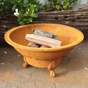 Lareira externa de ferro fundido com bancos integrados, perfeita para área de convívio ao ar livre.